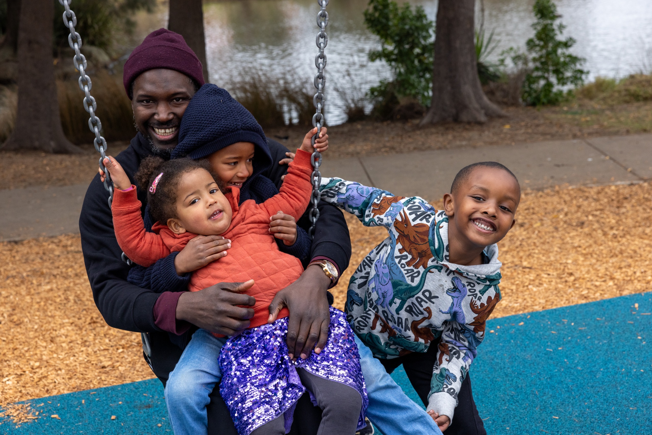 Father and three children on swing at playground